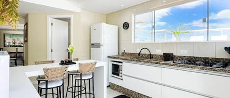 A modern kitchen with a large window, white cabinetry, and a built-in oven.