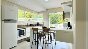 Une cuisine moderne dotée d’un îlot central, de tabourets de bar, d’un réfrigérateur et d’une cuisinière.