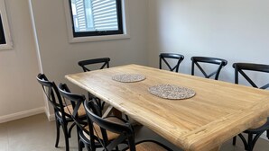 A dining table with four chairs, two placemats, and a window with blinds.