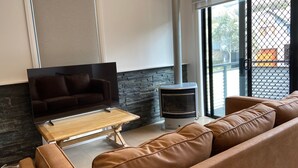 A living room with a TV, a stone wall, a fireplace, and a view through a glass door.