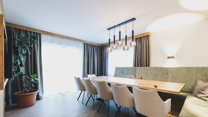 A modern dining area with a wooden table and chairs, a green sofa, and a potted plant. - Chalet Carina next ski slope (Zell am See)