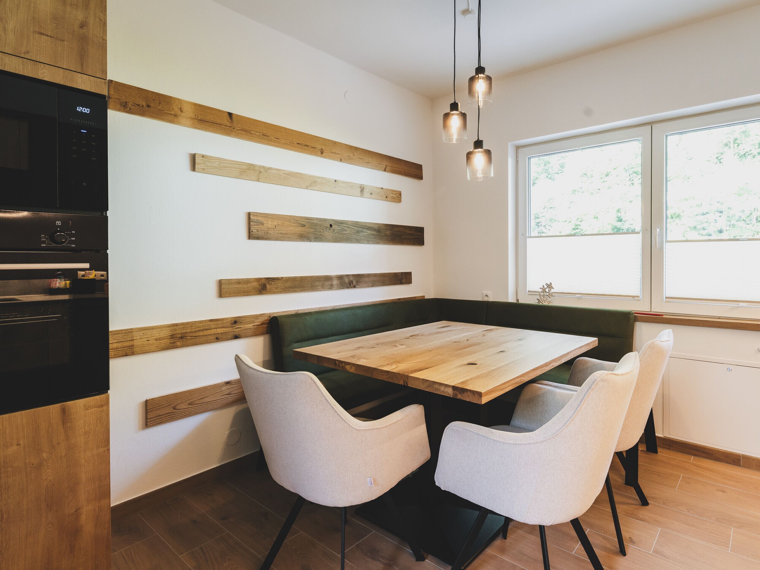 Een moderne keuken met een houten bank, een eettafel en stoelen.