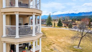 A multi-level building with balconies, a lawn, and a mountainous backdrop. - Satsuma | Close to Waterpark, Hot Springs & Golf (Fairmont Hot Springs)