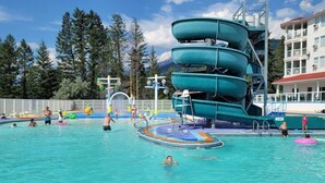 A swimming pool with multiple slides and a lifeguard stand. - Satsuma | Close to Waterpark, Hot Springs & Golf (Fairmont Hot Springs)