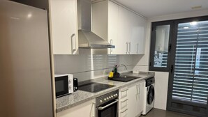 Eine moderne Küche mit weißen Schränken, einem Backofen, einer Mikrowelle, einem Kochfeld und einem Geschirrspüler.