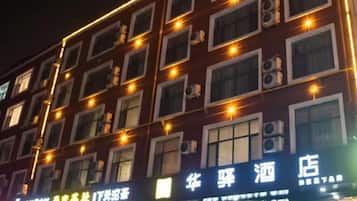 Une façade d’immeuble avec de nombreuses fenêtres et des enseignes lumineuses, indiquant la présence d’établissements commerciaux.