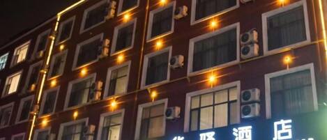 Fachada de edificio con múltiples ventanas y letreros iluminados, que señalan establecimientos comerciales.