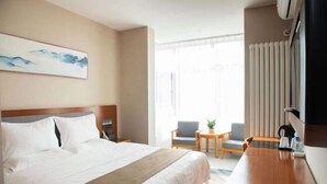 A hotel room with a bed, a desk, two chairs, a window, and a radiator. - Home Inn Huayi (Linyi Lanling Yucai Road) (Lanling)