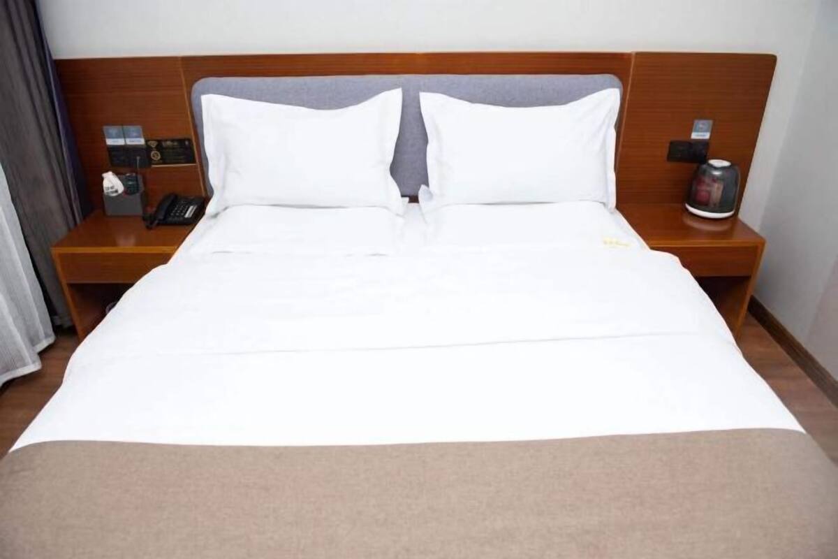 A hotel room with a large bed, two bedside tables, a telephone, and a coffee maker.