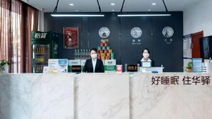 A hotel reception desk with clocks displaying New York and Paris times, a counter with various items, and a sign with Chinese characters. - Home Inn Huayi (Linyi Lanling Yucai Road) (Lanling)