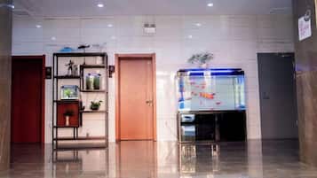 Un hall d’entrée avec un aquarium, une porte en bois et une étagère ornée d’objets décoratifs.