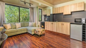 A modern kitchen with wooden cabinets, a built-in oven, and a microwave. - Warm Getaway 24/7 Power in Kfardebian (Jabal Lubnan)