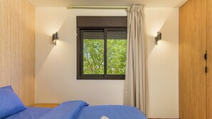 A bedroom with a bed, a window with a view of trees, and a wooden wardrobe. - Warm Getaway 24/7 Power in Kfardebian (Jabal Lubnan)