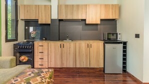 A compact kitchen with wooden cabinets, a microwave, a stove, and a refrigerator. - Warm Getaway 24/7 Power in Kfardebian (Jabal Lubnan)