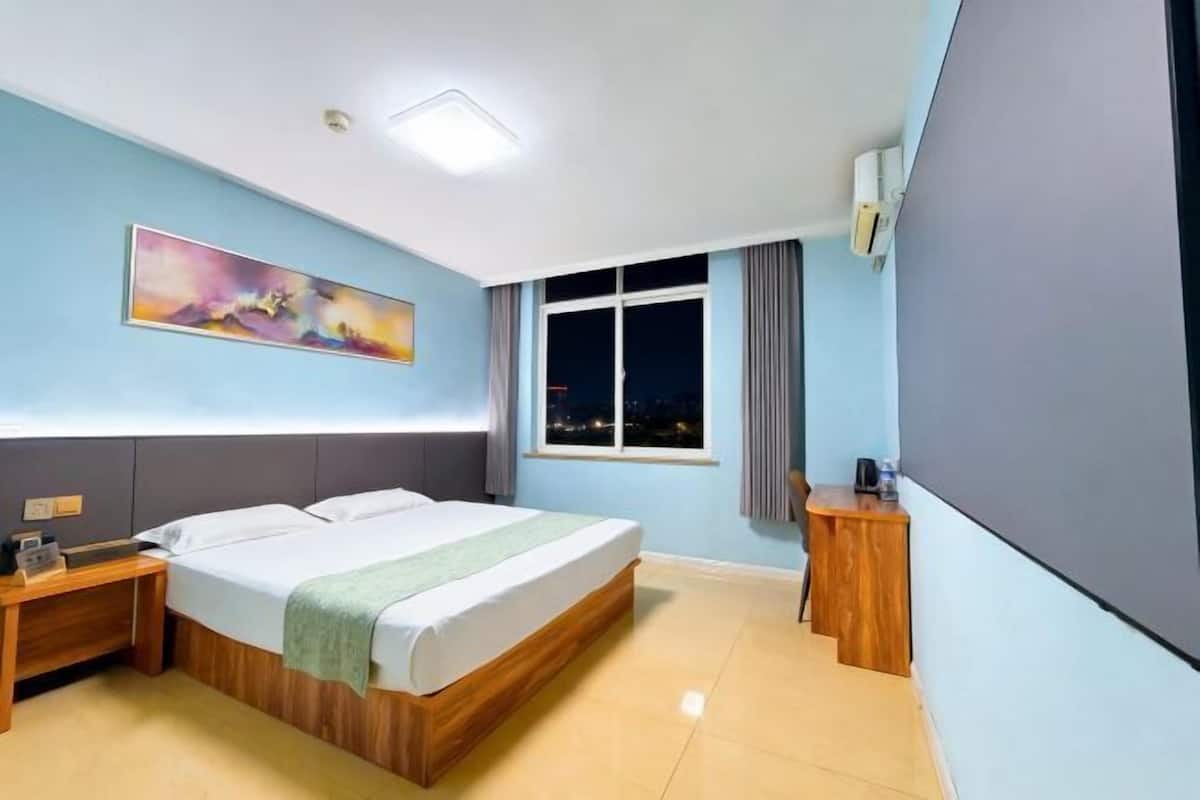Una habitación de hotel con cama, mesita de noche y un cuadro en la pared.