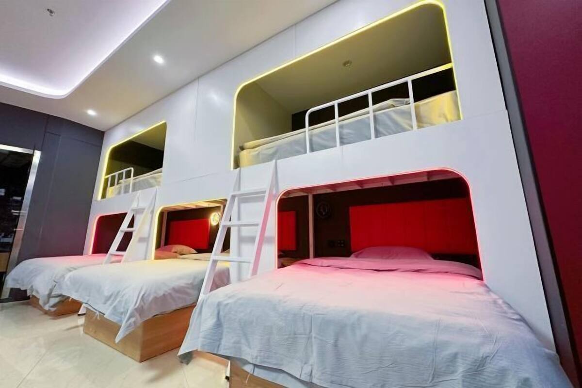 Una habitación con literas, una escalera y una pared de acento roja.