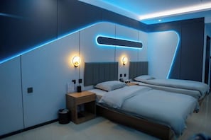 Una habitación de hotel moderna con un diseño geométrico único en la pared, dos camas, mesitas de noche e iluminación de pared.