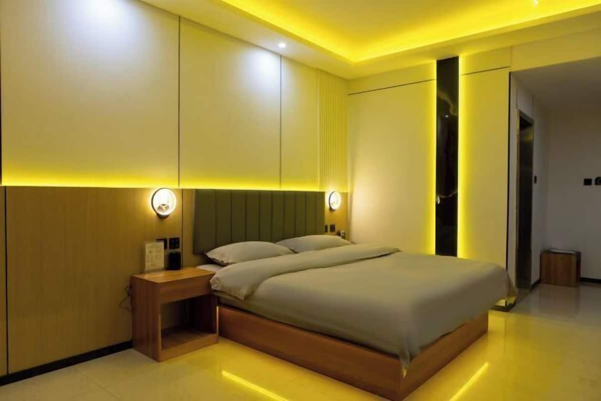 Un dormitorio moderno con cama, mesitas de noche e iluminación en la pared.