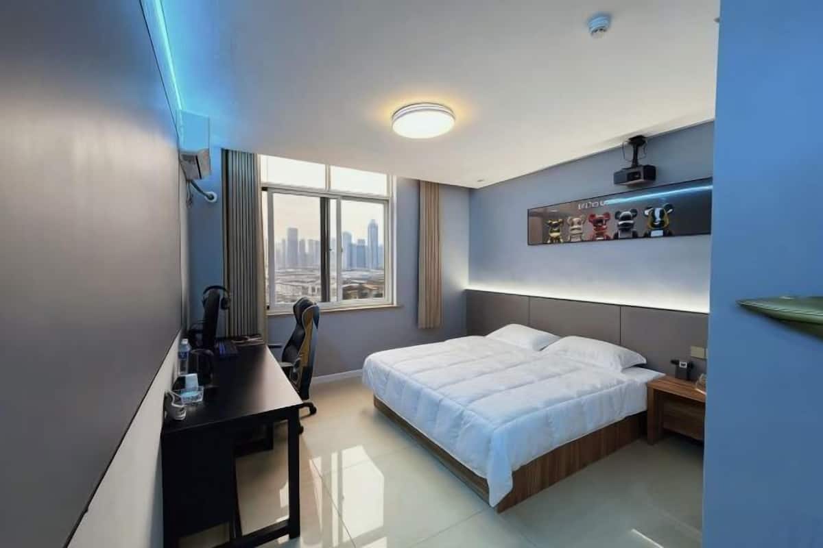 Una habitación de hotel moderna con cama, escritorio, silla y vista a la ciudad.