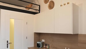 A modern kitchen with white cabinets, a built-in oven, a sink, and a countertop with a toaster and condiment bottles. - Cracow Vistula Boulevard #1 - Old Town (Kraków)