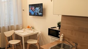 A modern kitchen with a dining area, a TV mounted on the wall, and a sink. - Cracow Vistula Boulevard #1 - Old Town (Kraków)