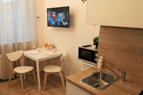 A modern kitchen with a dining area, a TV mounted on the wall, and a sink. - Cracow Vistula Boulevard #1 - Old Town (Kraków)