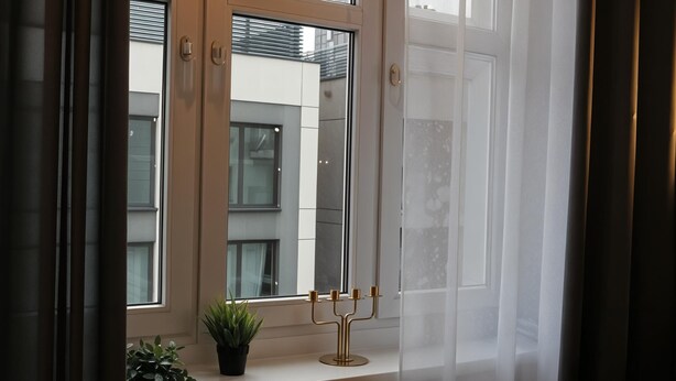 A window with a brass candelabra and a potted plant on a white ledge. - Cracow Vistula Boulevard #1 - Old Town (Kraków)