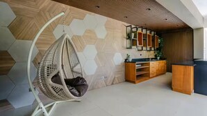 A modern interior with a hanging chair, wooden cabinets, and a geometric patterned wall.