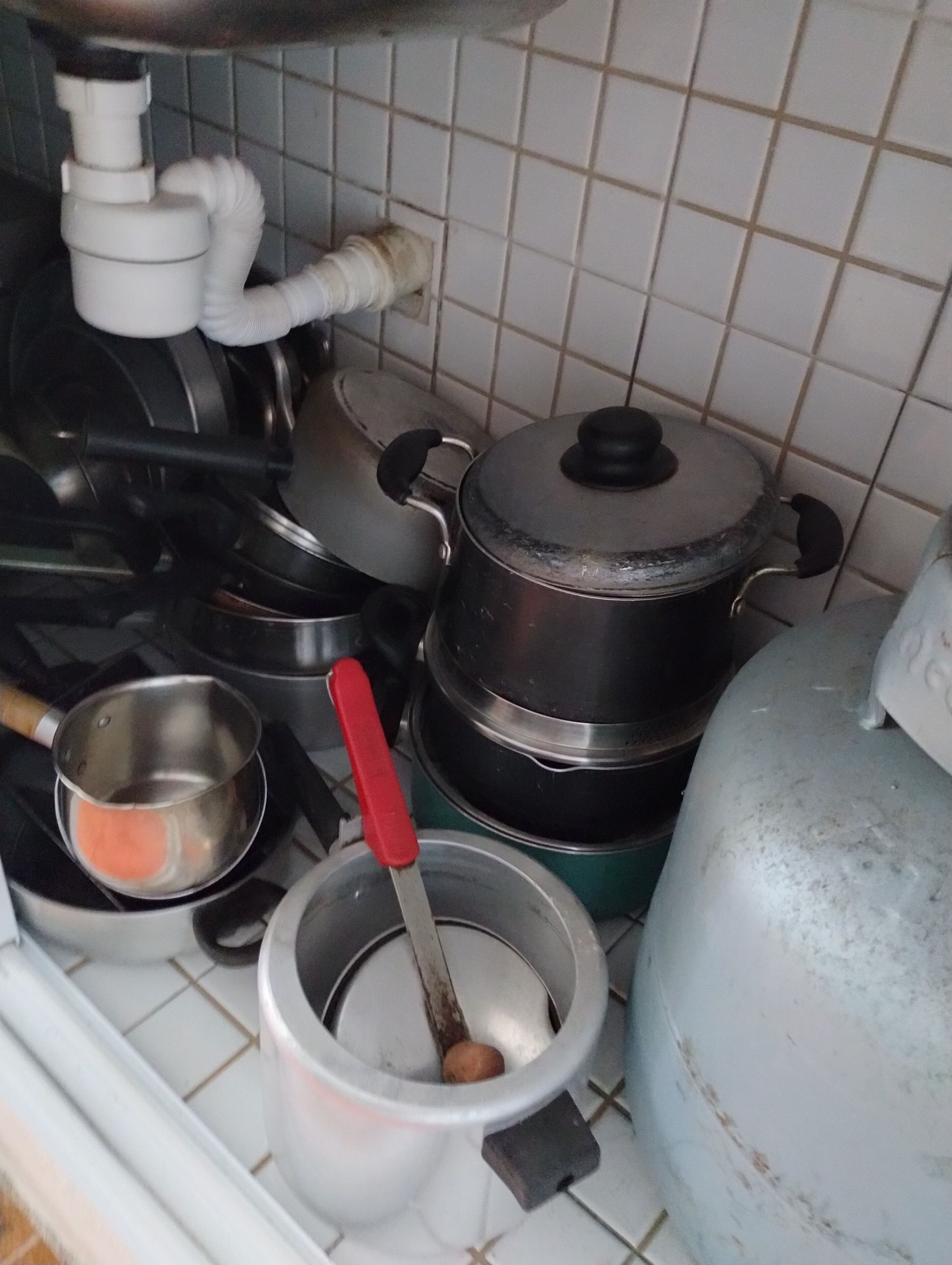 Una cuina amb diferents olles i cassoles, una cuina a gas i un dispensador d'aigua.