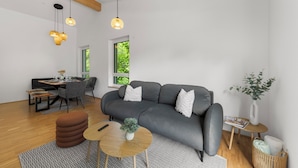 Una sala de estar moderna con un sofá gris, una mesa de centro de madera y lámparas colgantes.