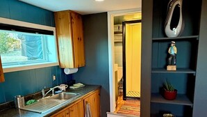 Une cuisine de taille réduite, avec des meubles de rangement en bois, un évier et une fenêtre.