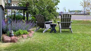 Un espace extérieur aménagé avec des chaises Adirondack, une petite table et une structure métallique décorative.