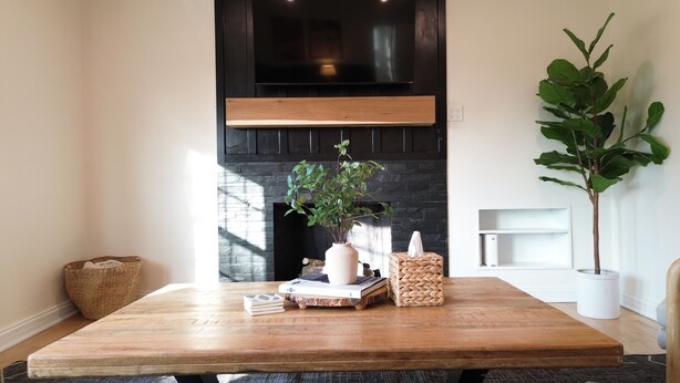 A modern living room with a large wooden table, a black fireplace, and a potted plant. - Modern Mission Escape Home - Family Friendly - Close to All Attractions (Mission)