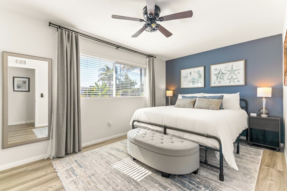 A bedroom with a bed, a ceiling fan, a nightstand, and a window with curtains.