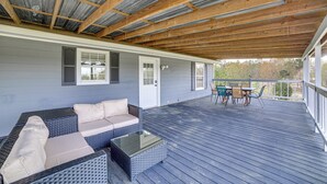 Una terraza techada con mobiliario exterior, una mesa de vidrio y vistas del entorno.