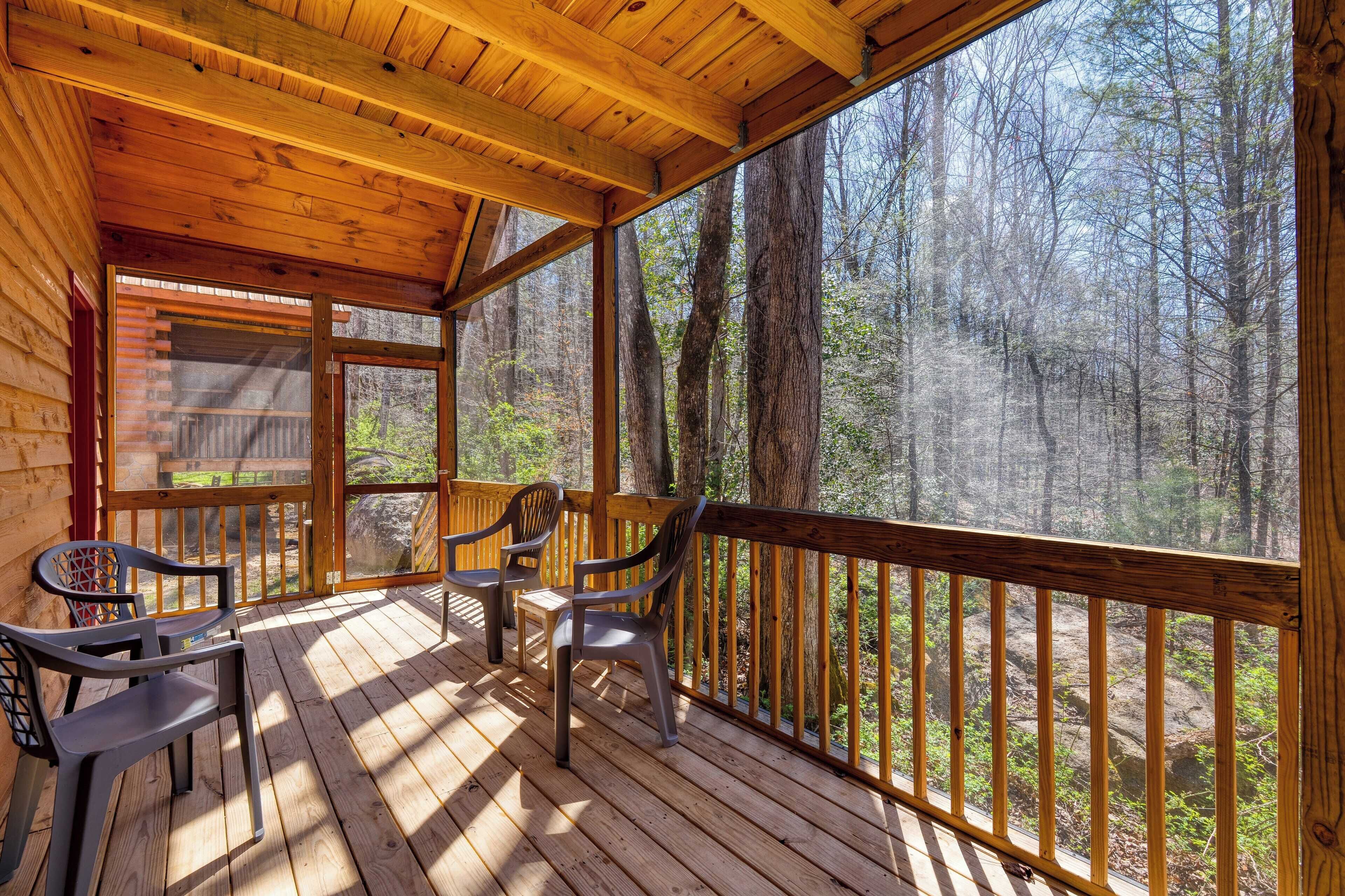 A wooden deck with chairs and a view of a forest.