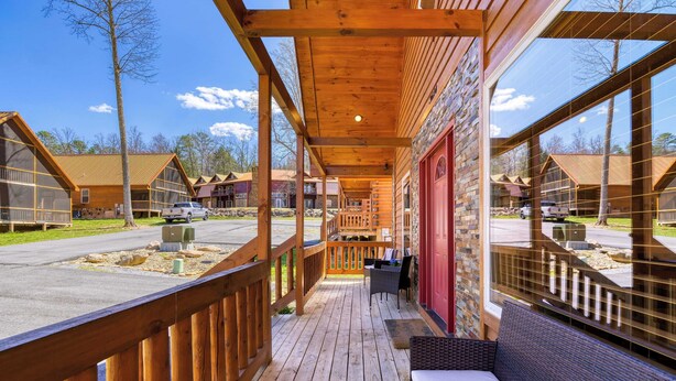 A wooden deck with a bench, a red door, and a view of other cabins. - Hot Tub + Foosball Access to Pool, Tennis, Gym Chill'n in the Smokies (Gatlinburg)