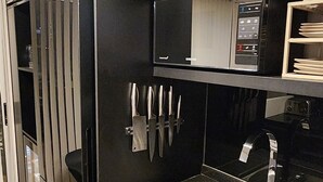 A modern kitchen with a stainless steel sink, black cabinetry, and a microwave on a black shelf.