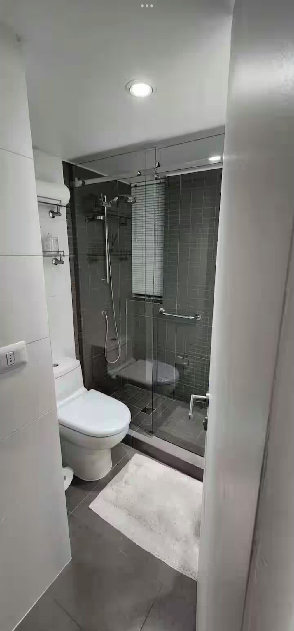 A modern bathroom with a glass-enclosed shower, a toilet, and a white sink.