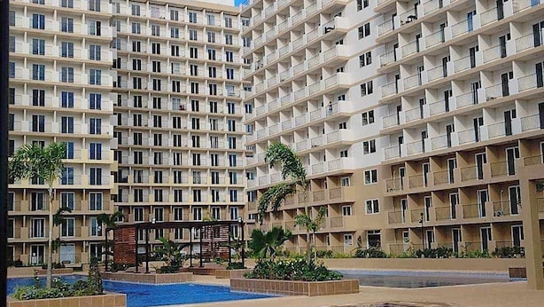 Un hotel de varios pisos con una piscina al frente.