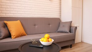 Ett modernt vardagsrum med en grå soffa, en skål med citroner på ett soffbord och en vit tegelvägg.