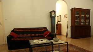 Una sala de estar con un sofá, una mesa de centro, un reloj, un mueble y una alfombra.