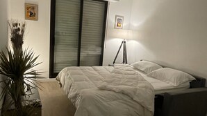 Een slaapkamer met een bed, bedlampje en een potplant.