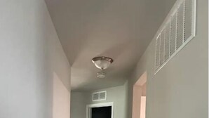 A hallway with a wooden floor, a ceiling vent, and a door leading to a dark room. - Charming 3-bedroom house with AC, WiFi in beautiful Lander (Lander)