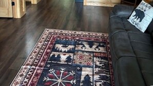 A log cabin interior with a ceiling fan, a black leather sofa, and a patterned rug. - Cozy 2 bedroom cottage with heated pool AC in charming New Hope (New Hope)
