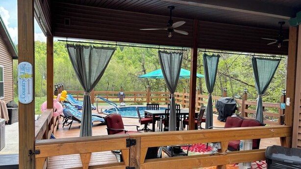 A covered outdoor area with a pool, lounge chairs, and umbrellas. - Cozy 2 bedroom cottage with heated pool AC in charming New Hope (New Hope)