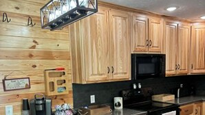 A kitchen with wooden cabinets, a granite countertop, a coffee maker, and a microwave. - Cozy 2 bedroom cottage with heated pool AC in charming New Hope (New Hope)