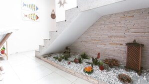 A modern interior with a staircase leading to a wooden wall, a small garden area with plants, and decorative items. - Bz24 Geribá 350 metros da praia 4 Suítes (Buzios)