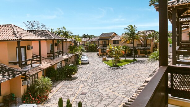 A courtyard with traditional architecture, stone paving, and palm trees. - Bz24 Geribá 350 metros da praia 4 Suítes (Buzios)