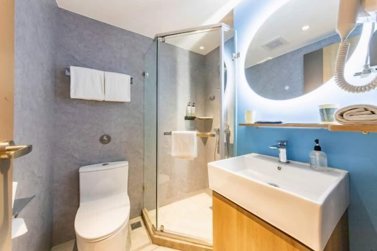 A modern bathroom with a glass-enclosed shower, a white sink, and a wooden cabinet.